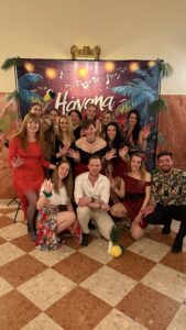Group of friends in tropical party outfits posing for a photo in front of a Havana-themed backdrop.